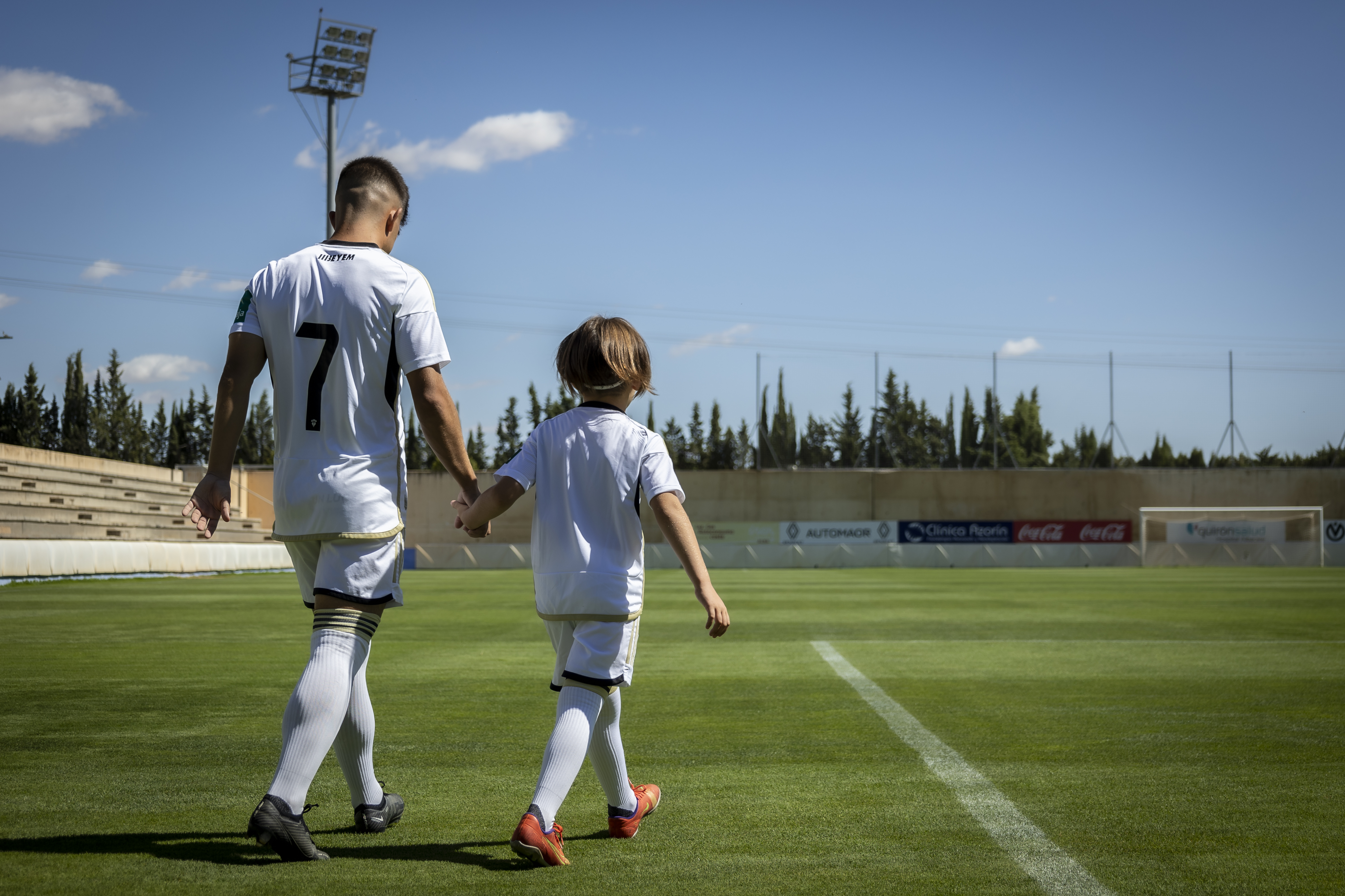 Jugador del Albacete Balompié con un niño de la mano.